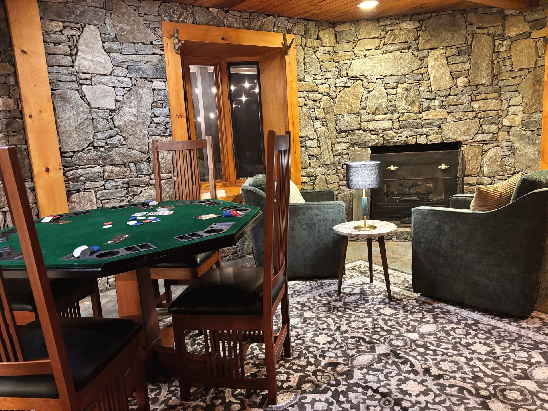 Game room with poker table and stone wall fireplace