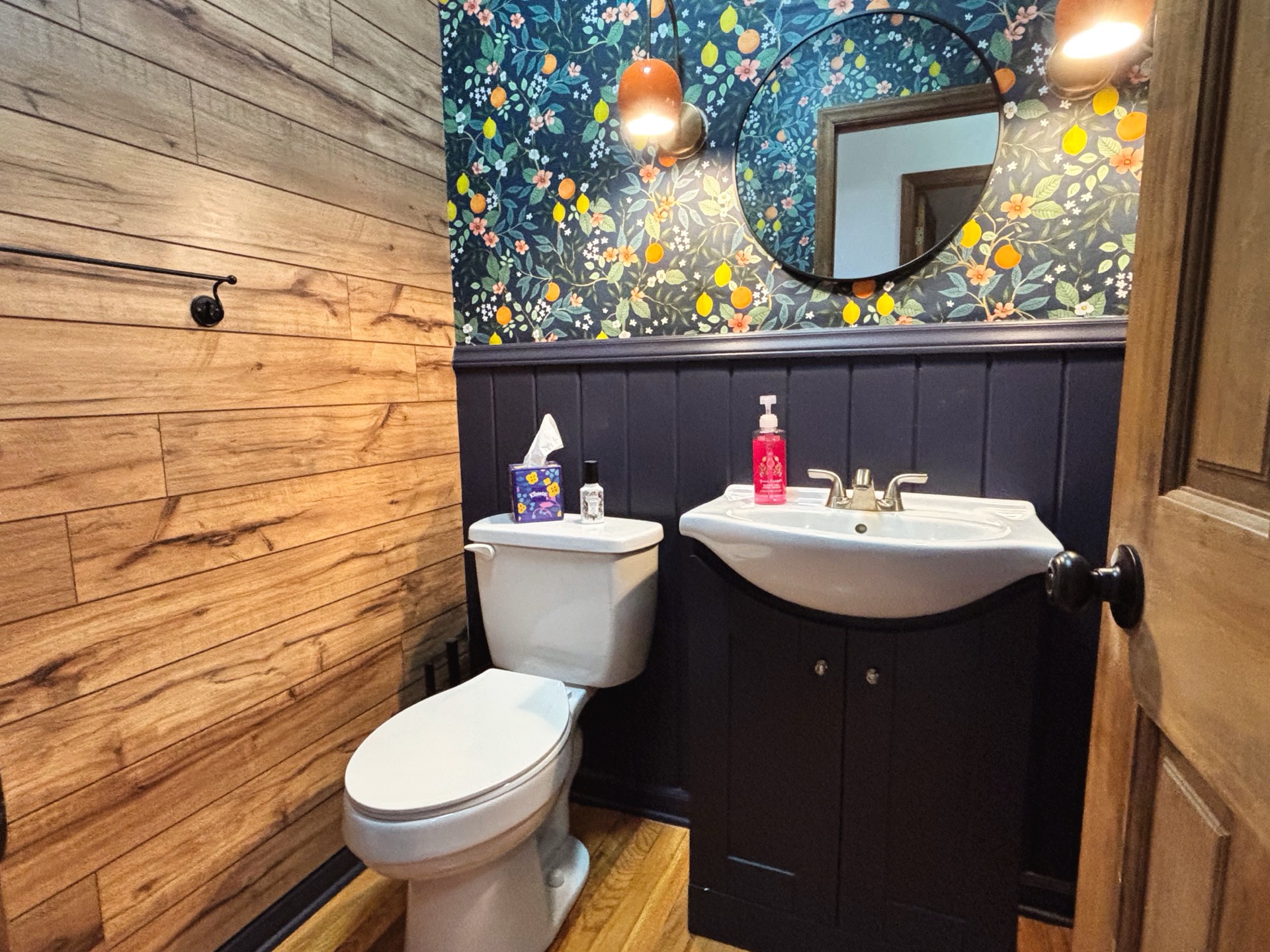Half bath with floral wallpaper and dark wainscoting